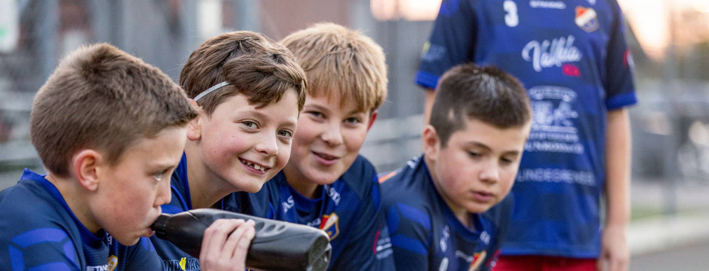 Pojkar i fotbollslag sitter pa en bank