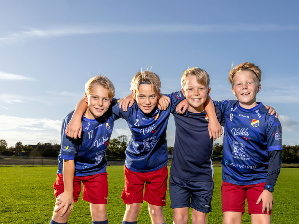 Glada pojkar på en fotbollsplan som håller om varandra