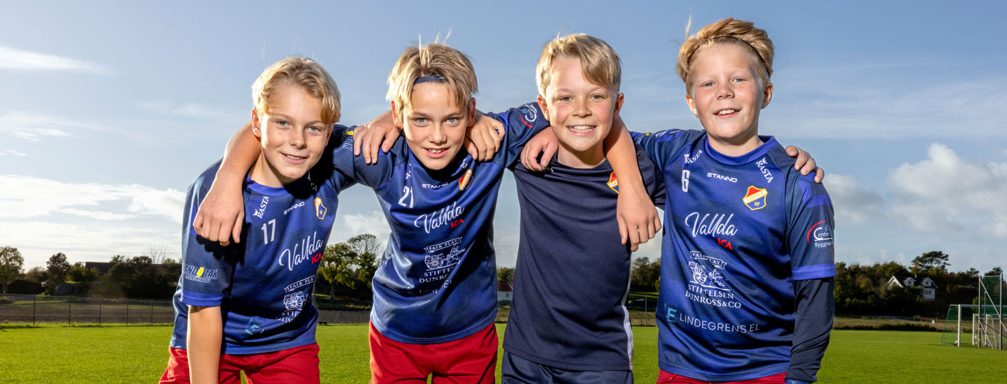 Glada pojkar på en fotbollsplan som håller om varandra