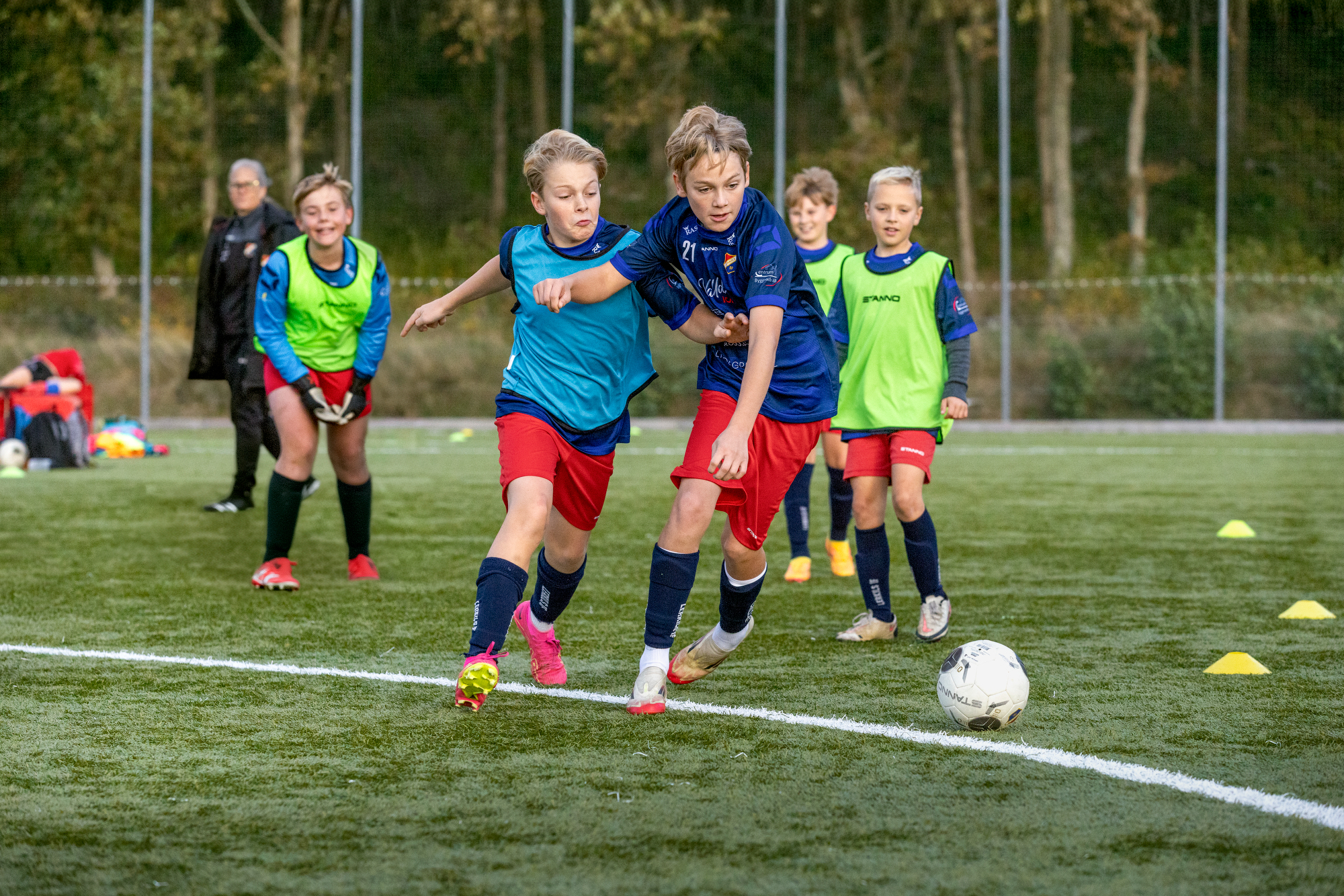 Pojkar som spelar fotboll, varav två av dem i intensiv närkamp om bollen