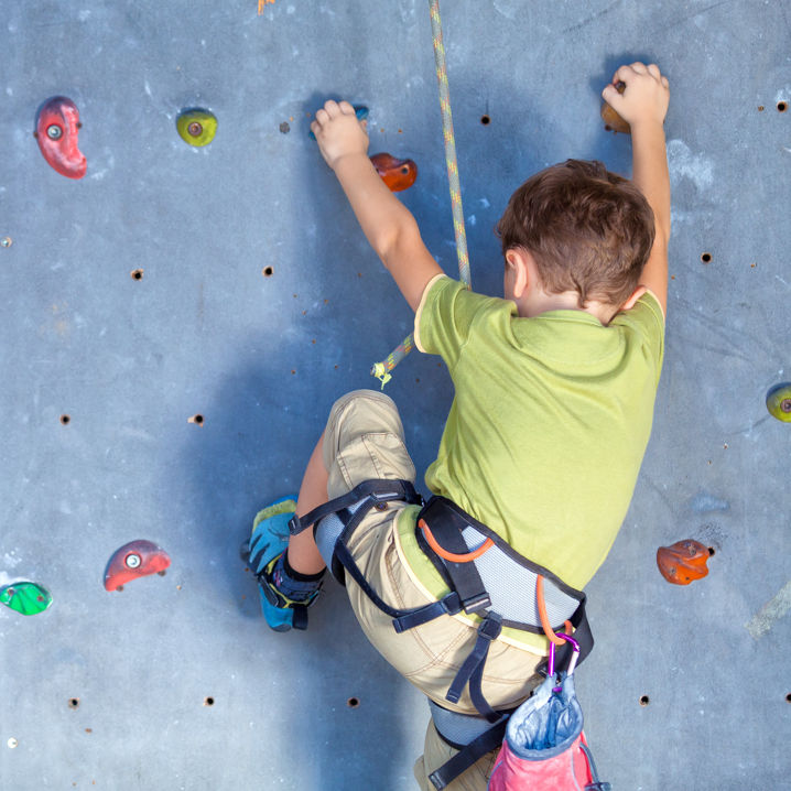 Ett barn iklädd klättringsutrustning som klättrar på en klättervägg