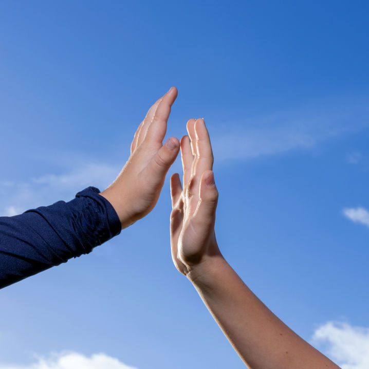 Två händer som gör high five i luften