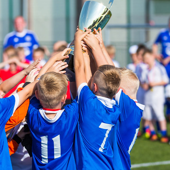 Pojkar i blått matchställ lyfter en pokal över sina huvuden