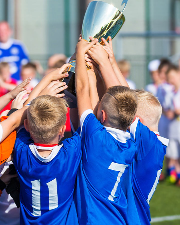 Pojkar i blått matchställ lyfter en pokal över sina huvuden