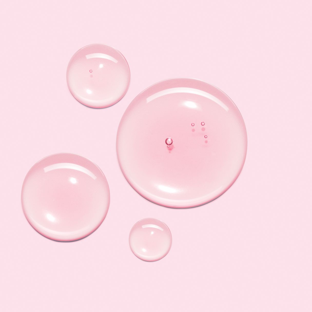 Rosa bakgrund med fyra transparenta vattendroppar i olika storlek