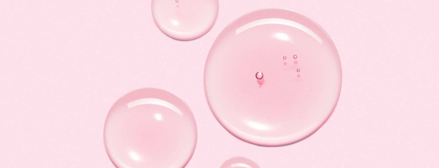 Rosa bakgrund med fyra transparenta vattendroppar i olika storlek