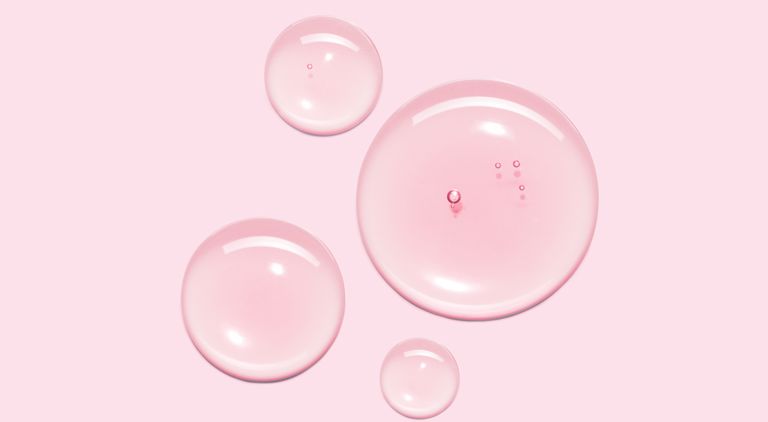 Rosa bakgrund med fyra transparenta vattendroppar i olika storlek