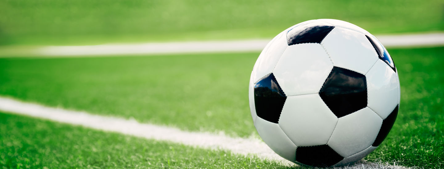 En fotboll i svart och vitt liggandes på en vit linje på en gräsplan