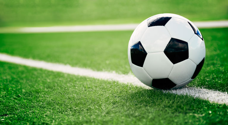 En fotboll i svart och vitt liggandes på en vit linje på en gräsplan