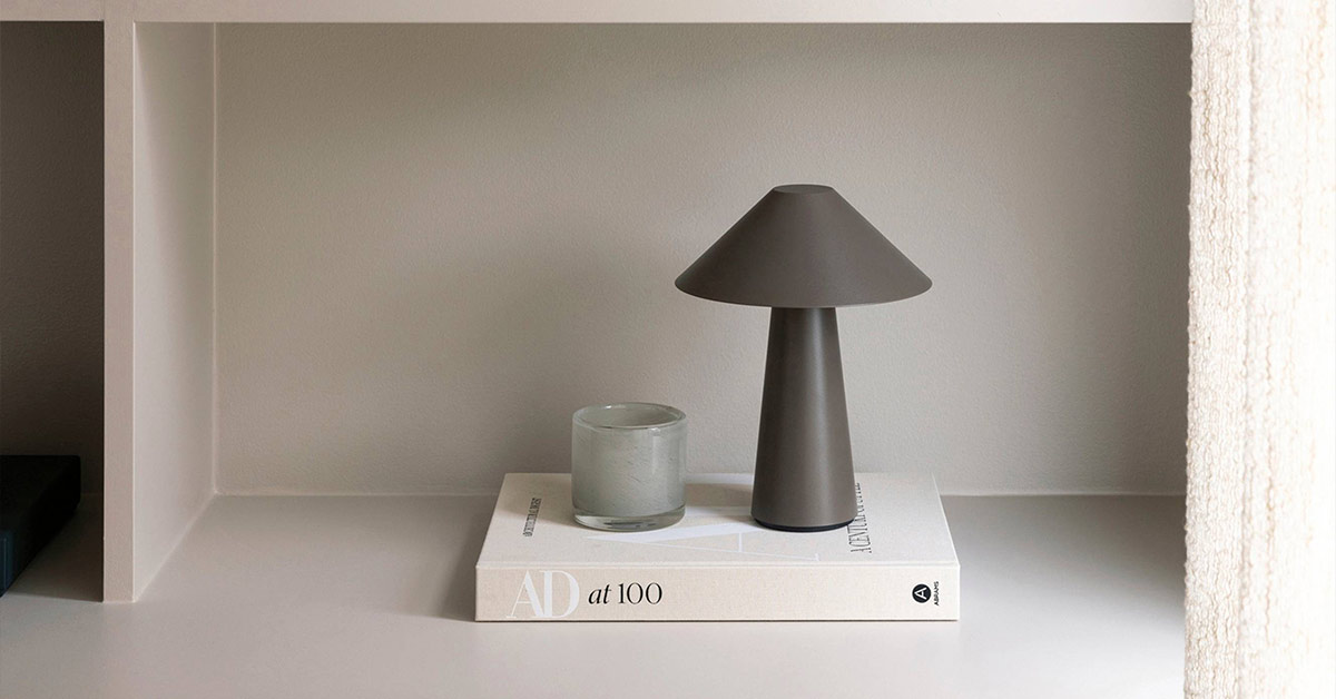 Lampa och ljuslykta stående på beige bok