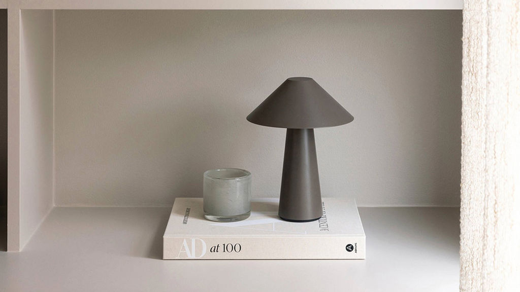 Lampa och ljuslykta stående på beige bok