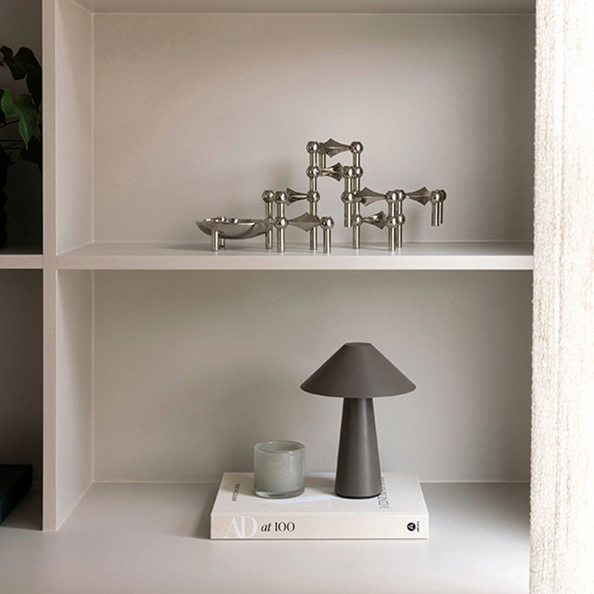 Lampa och ljuslykta stående på beige bok