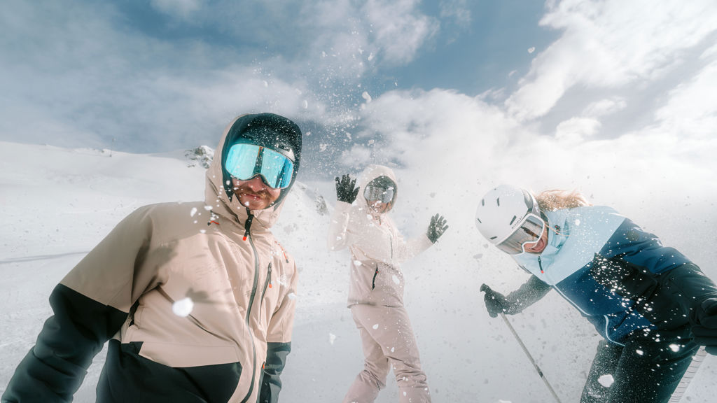 Tre personer som åker skidor och snowboard
