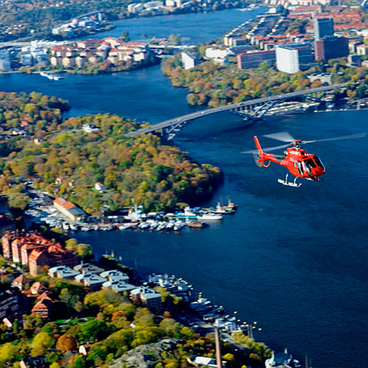 Röd helikopter som flyger över stort vatten