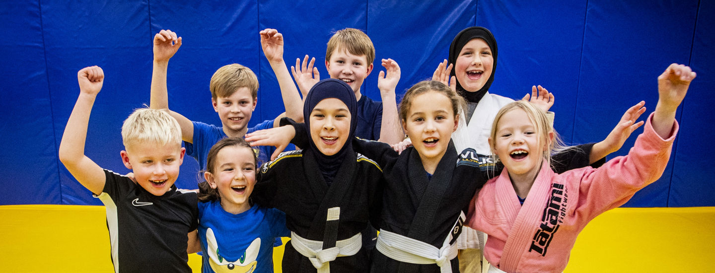 Glada barn som kramas och håller upp händerna i luften