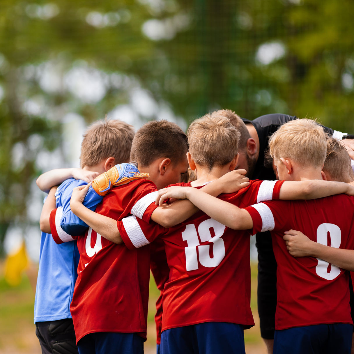 Pojkar som kramas i en ring på fotbollsplan
