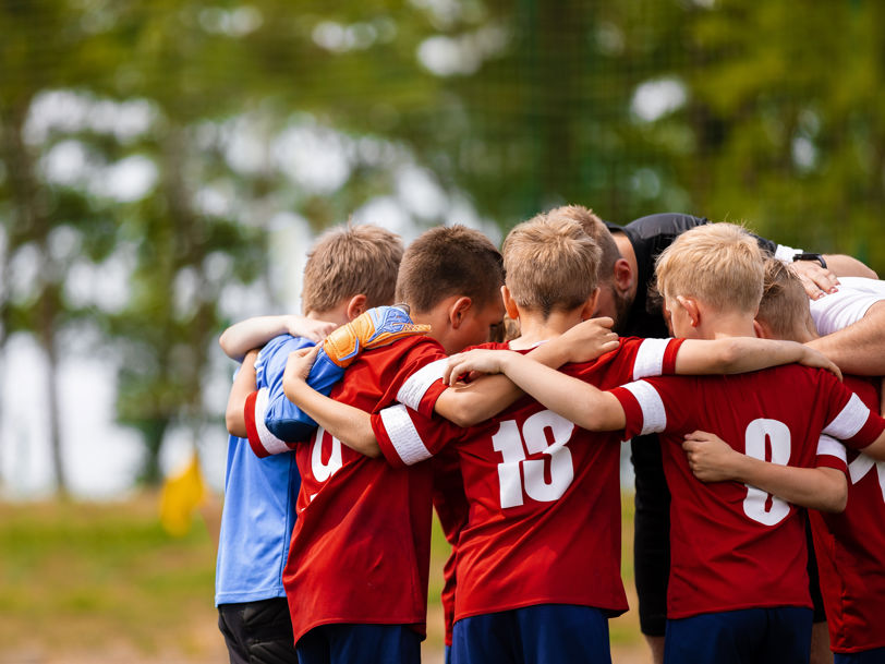 Pojkar som kramas i en ring på fotbollsplan