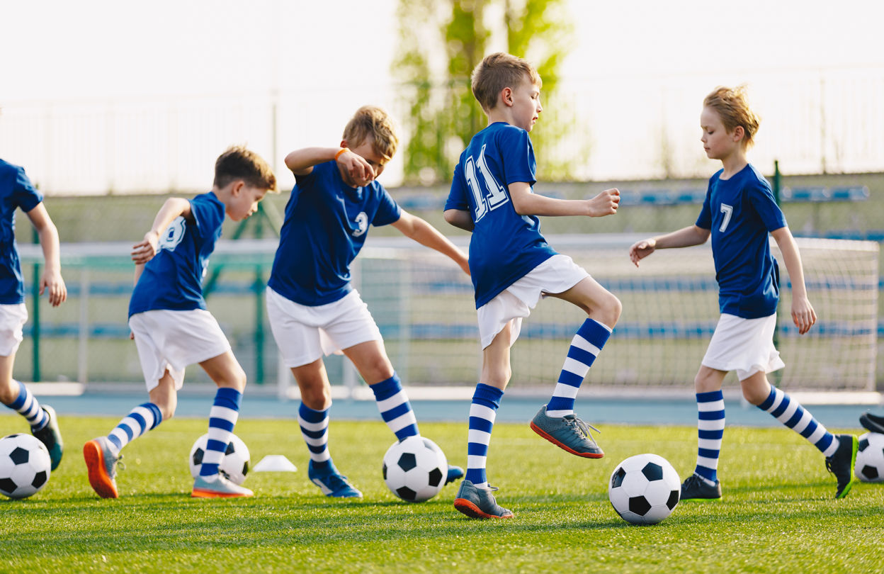 Pojkar i blåvita matchkläder aktiverar sig med varsin boll på plan