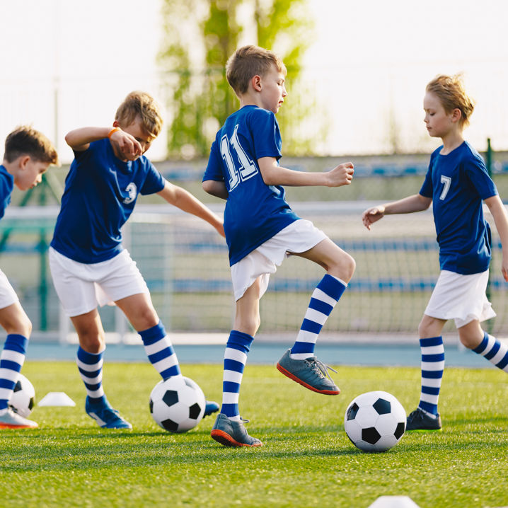 Pojkar i blåvita matchkläder aktiverar sig med varsin boll på plan