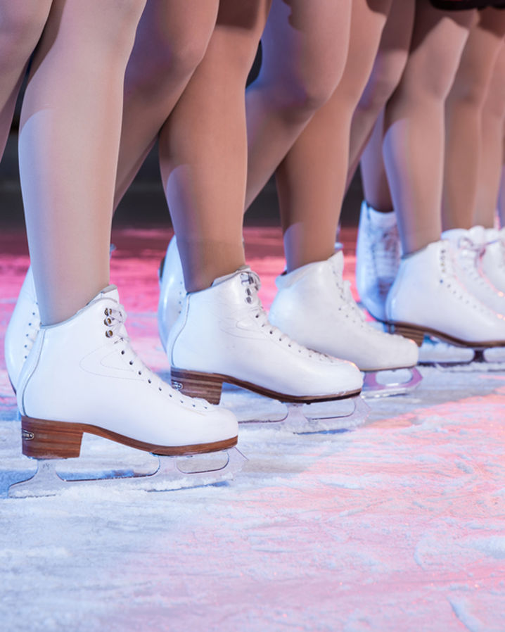 Konståkare i rad på is med vita skridskor.