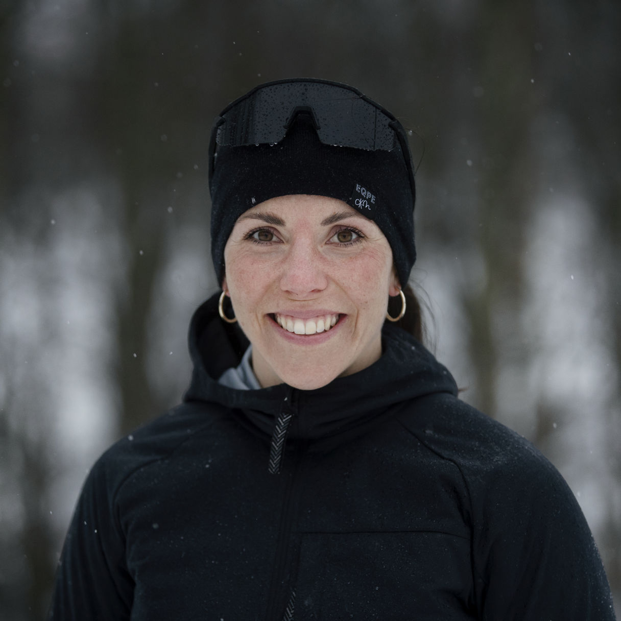 Charlotte Kalla i vintermiljö med svart mössa och jacka, tittar in i kameran.