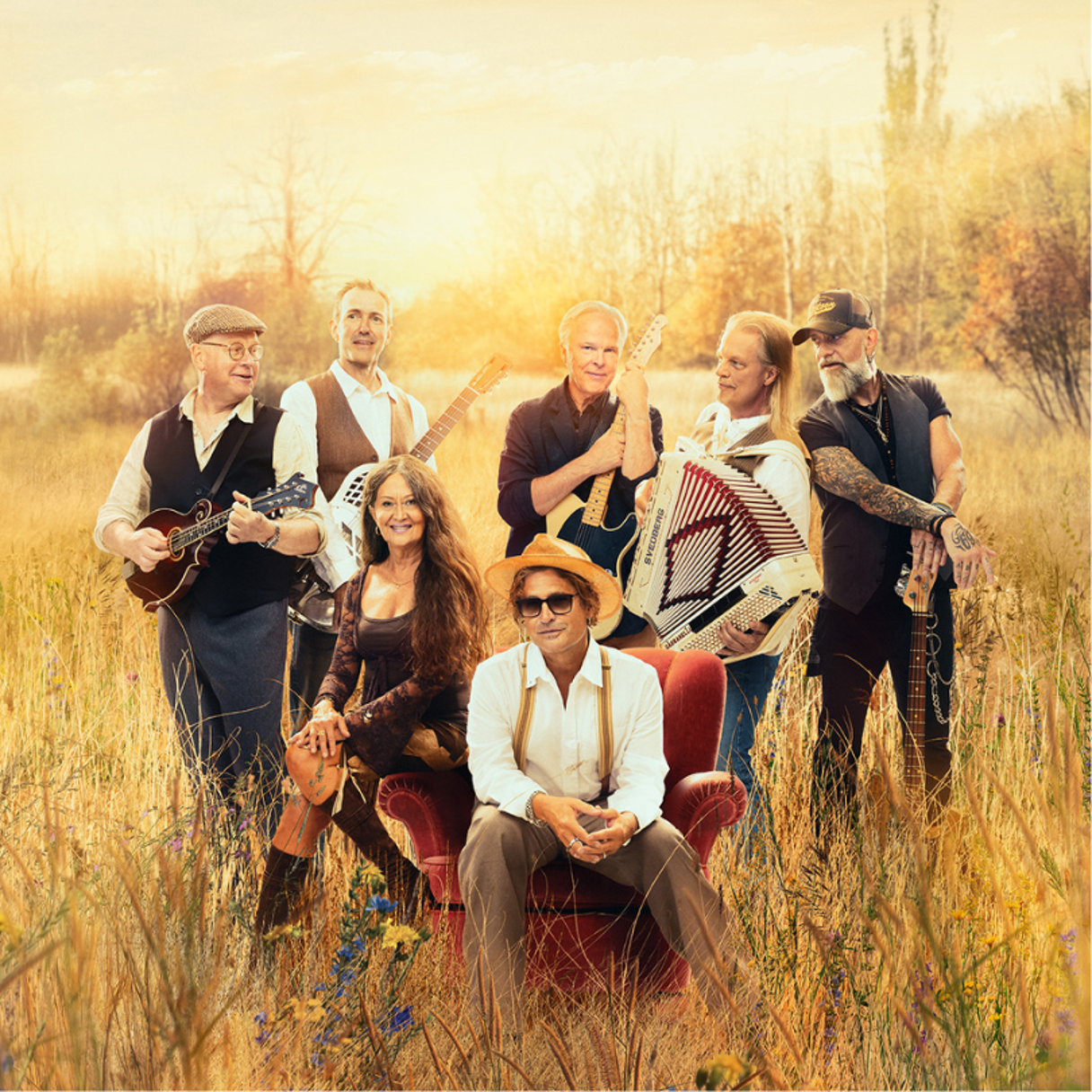 Musiker sitter på ett fält i solnedgång