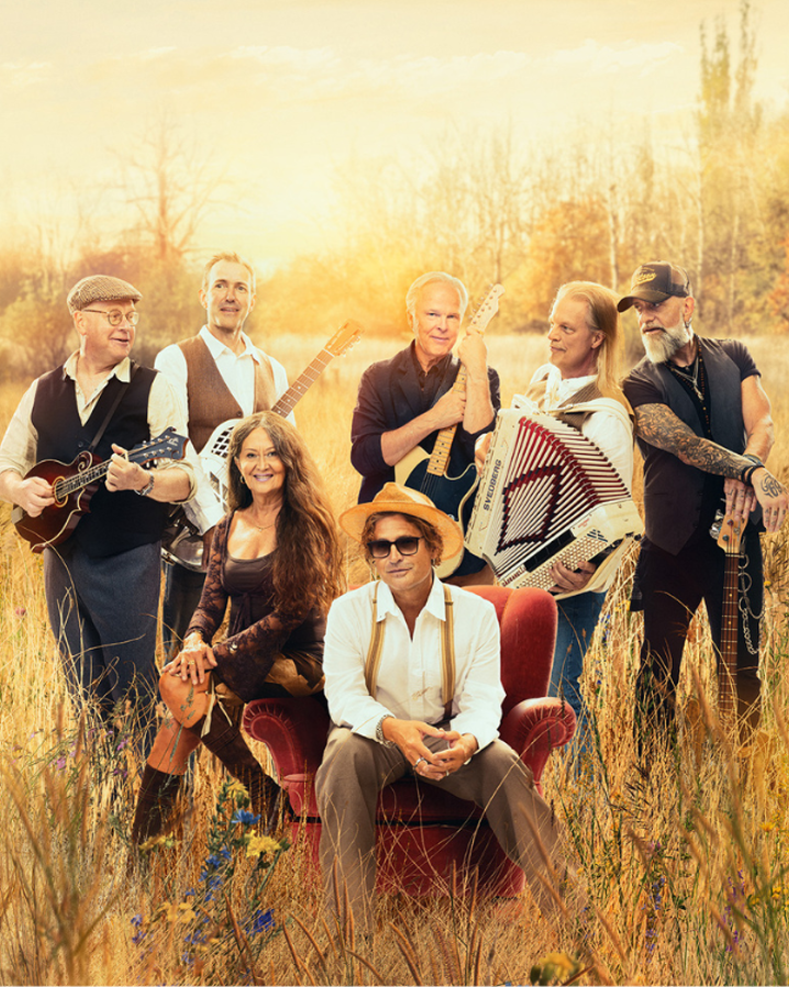 Musiker sitter på ett fält i solnedgång