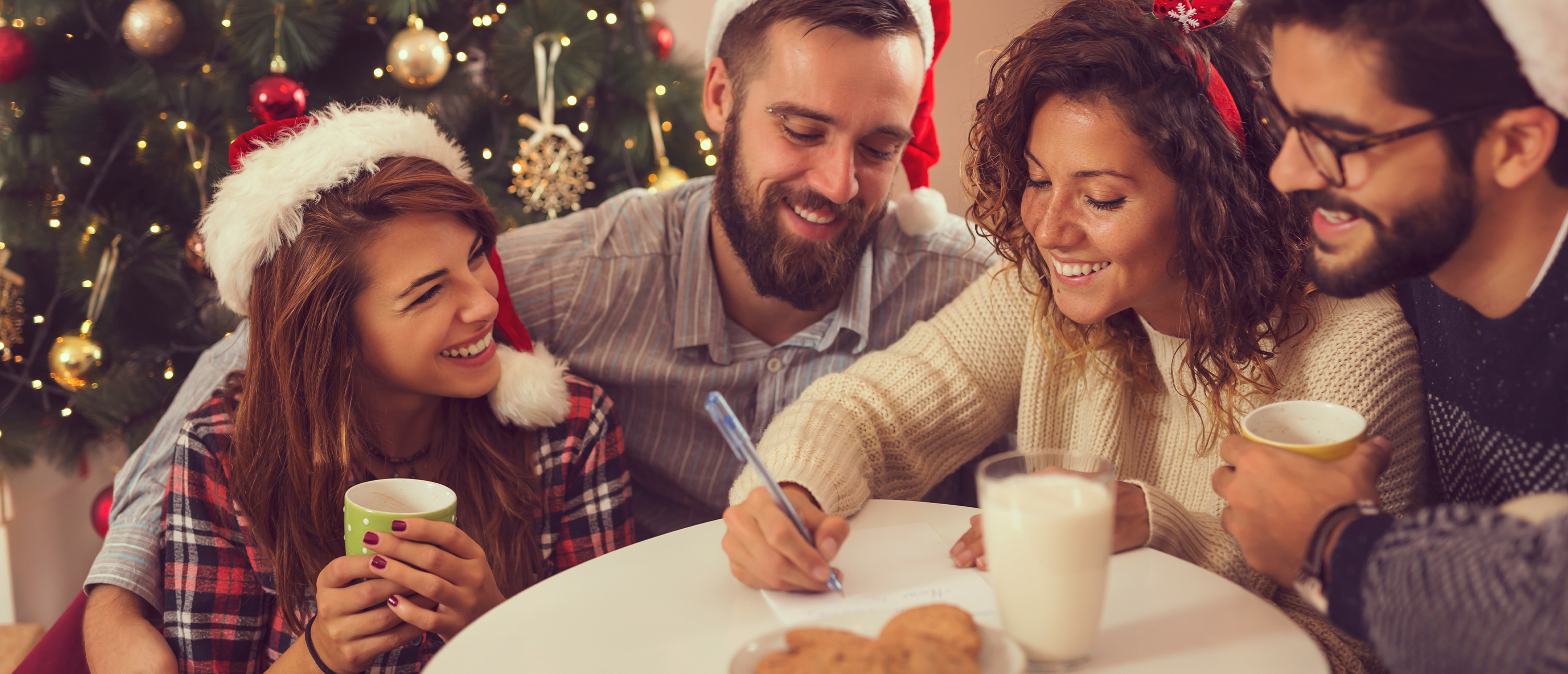 En samling vänner med tomtemössor i ett juligt inrätt rum dricker kaffe och quizar tillsammans