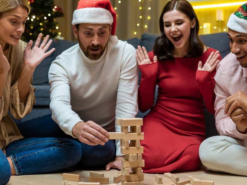 En grupp vänner spelar JENGA, iförda tomtemössor
