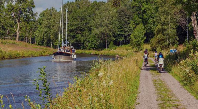 Cyklister och en båt i en kanal i ett idylliskt landskap