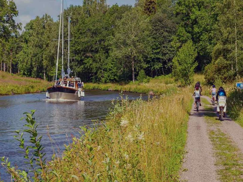 Cyklister och en båt i en kanal i ett idylliskt landskap