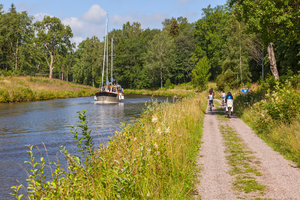 Cyklister och en båt i en kanal i ett idylliskt landskap