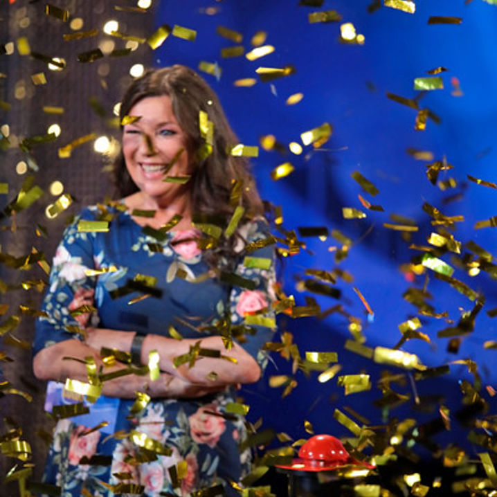 En leende Lotta Engberg i ett hav av guldfärgad konfetti