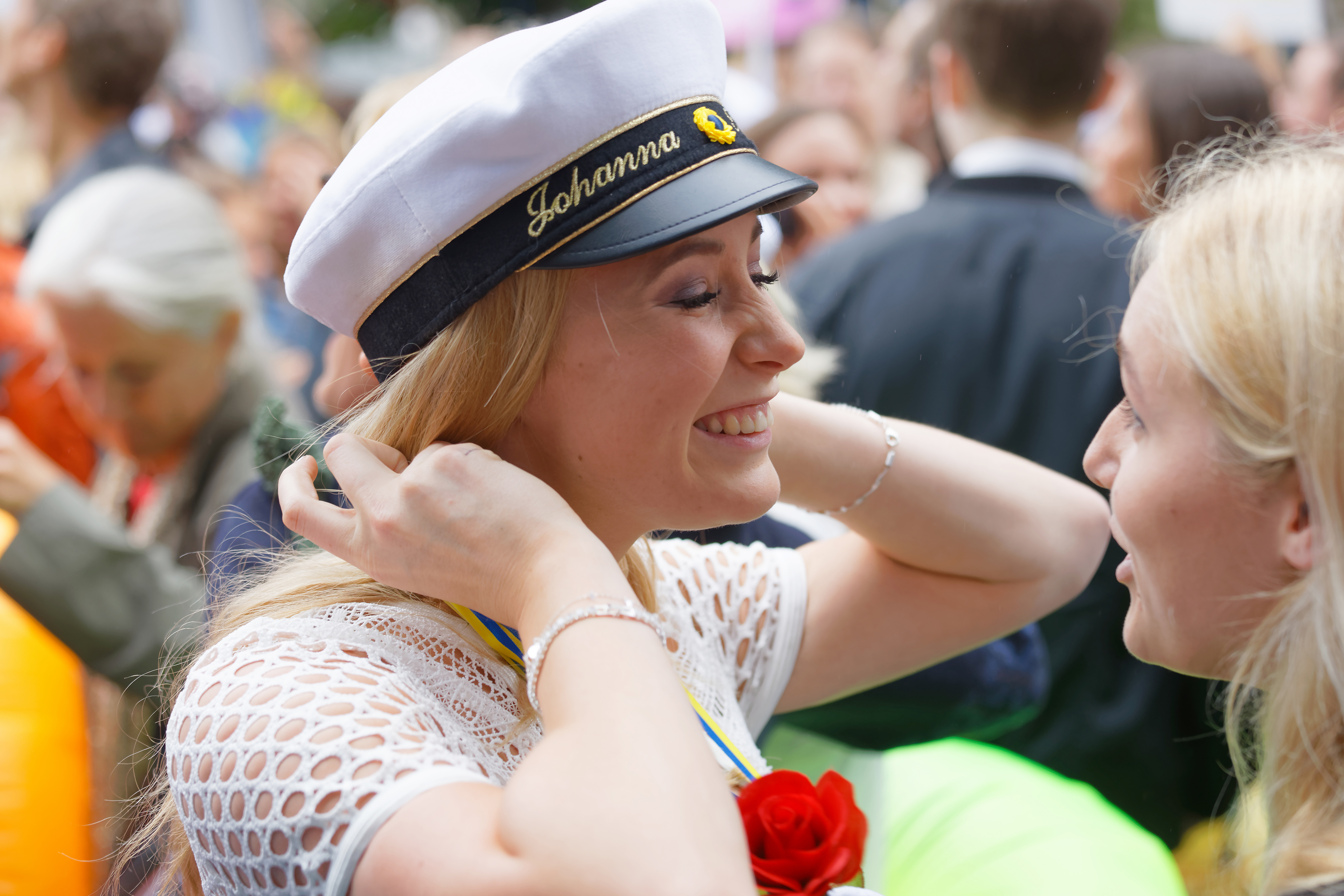 Glad tjej med studentmössa och ros runt halsen