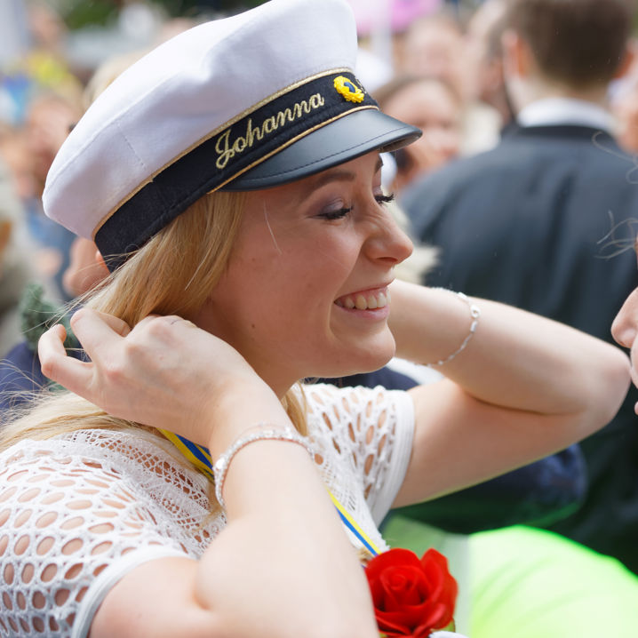 Glad tjej med studentmössa och ros runt halsen
