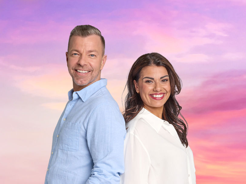 Programledarna för BingoLottos Sommarfest, Casper Janebrink och Carin Da Silva, framför en rosafärgad himmel