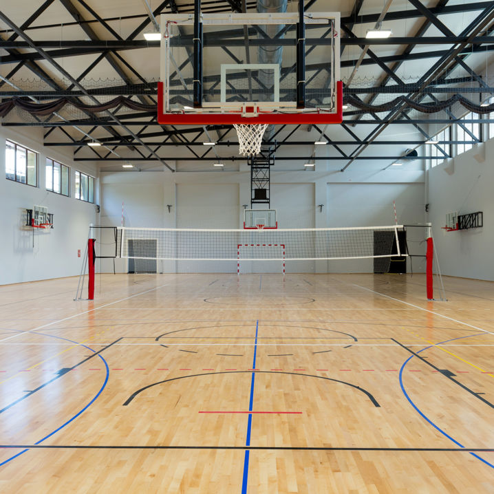 En tom idrottshallar med basketkorgar och volleybollnät