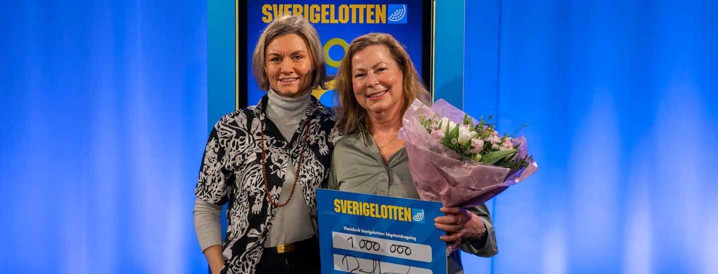 Två vinnare med Sverigelotten-check och blommor i vinstceremoni.