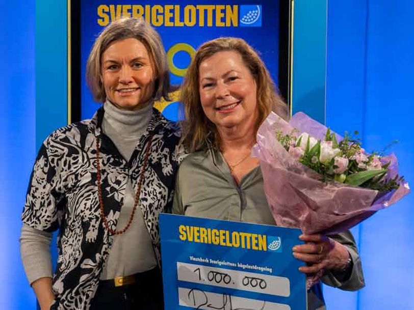 Två vinnare med Sverigelotten-check och blommor i vinstceremoni.