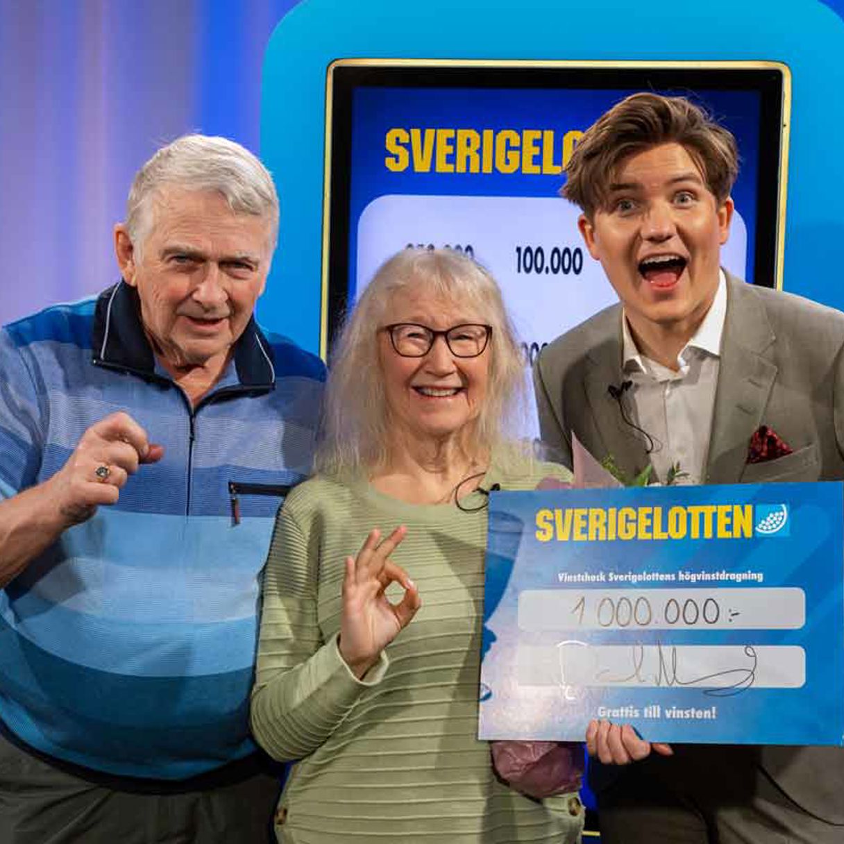 Två vinnare med Sverigelotten-check tillsammans med programledare.