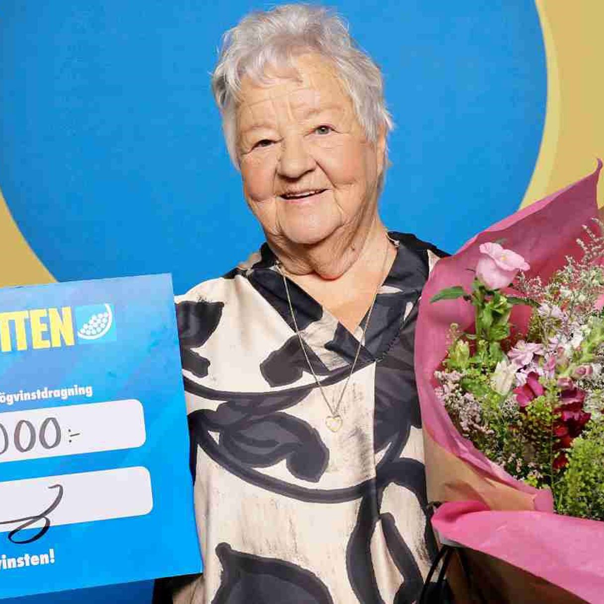 Vinnare med Sverigelotten-check och en blombukett.