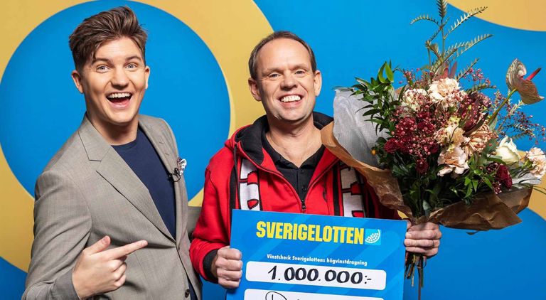 Vinnare med Sverigelotten-check och blommor tillsammans med programledare i studio.
