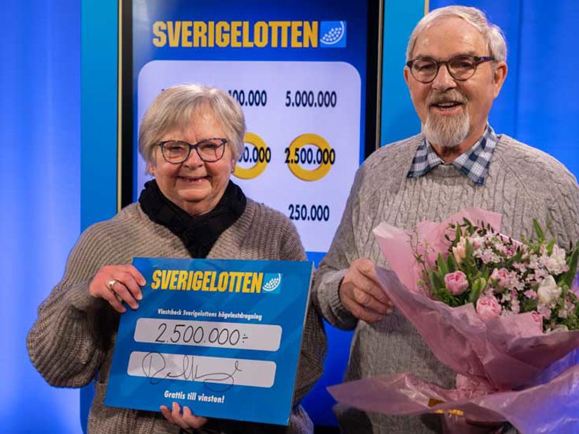 Två vinnare med Sverigelotten-check och blommor.