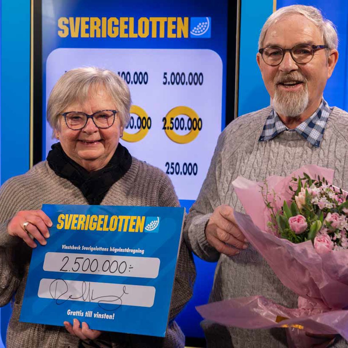 Jan-Erik Nilsson firar sin vinst på 2,5 miljoner kronor i Sverigelottens högvinstdragning med sin hustru, blommor och en Sverigelott.