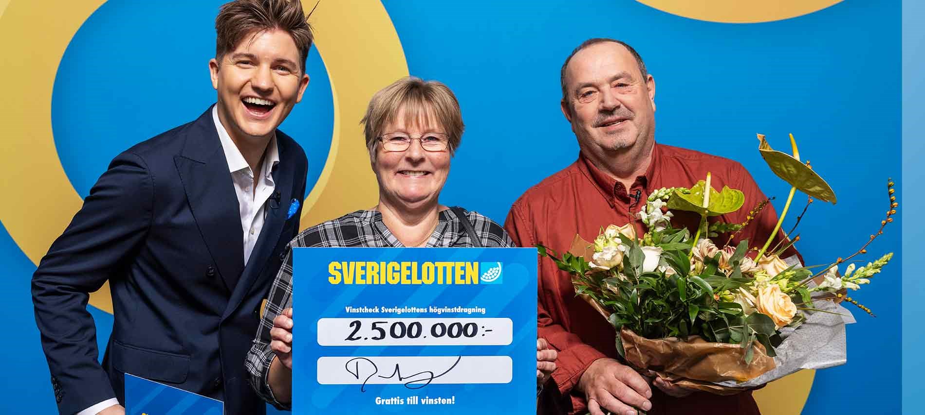 Vinnare med Sverigelotten-check och blommor tillsammans med programledare i studio.