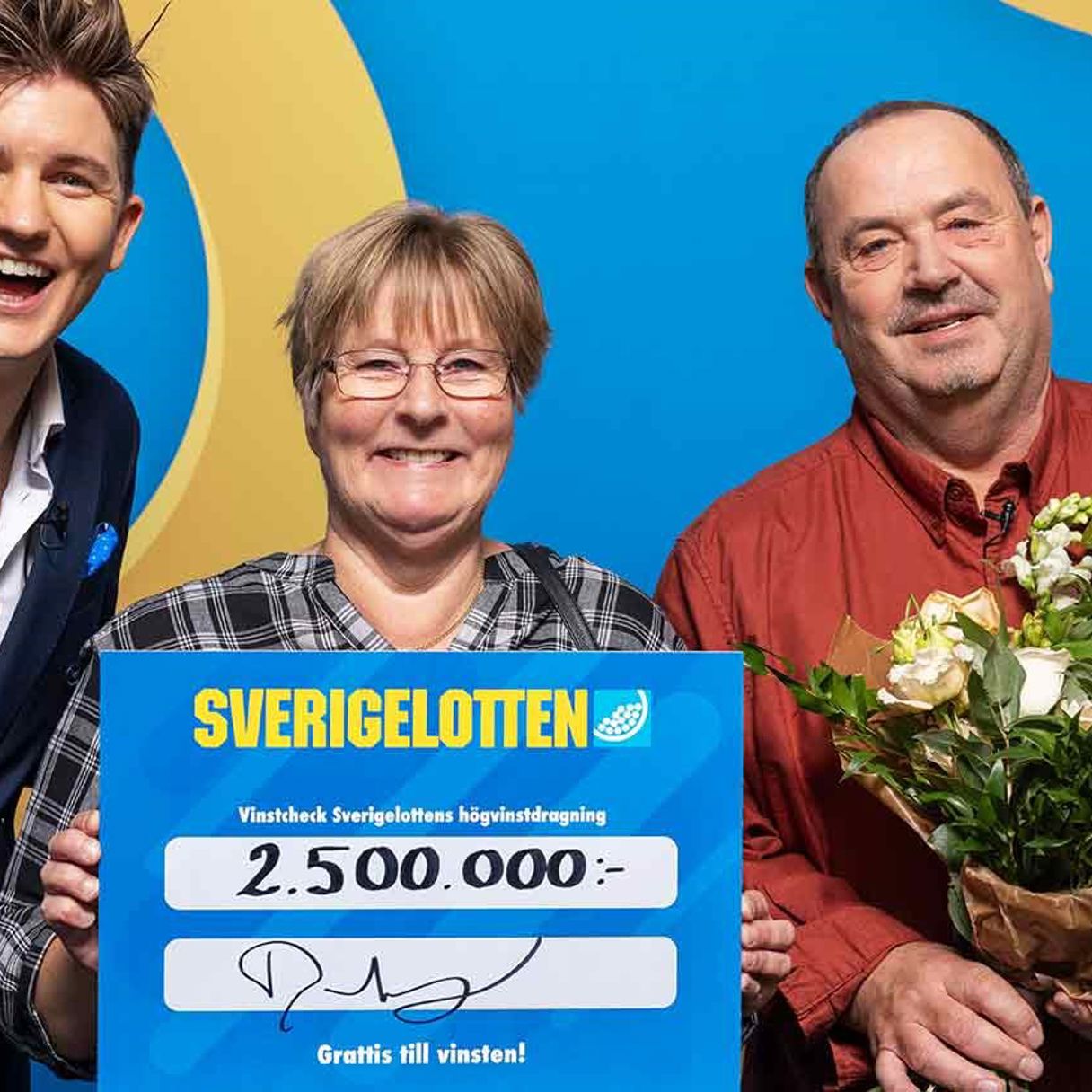 Vinnare med Sverigelotten-check och blommor tillsammans med programledare i studio.
